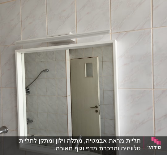 מראה תלויה על קיר אריחים בחדר אמבטיה